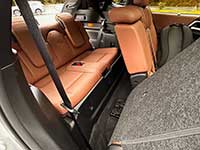 2026-Outlander-PHEV-seating • Edmonton's Business Cargo area of a car with orange-brown leather rear seats folded down, gray carpeting, and a visible seat belt.